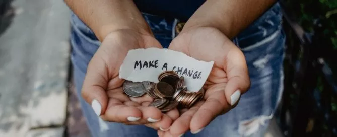 Argent dans mains avec une écriture "Make a change" sur un papier